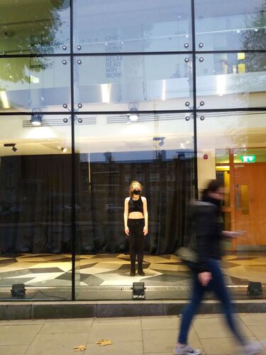 Niamh McPhillips framed in the windows of The Science Gallery as pedestrians walk by