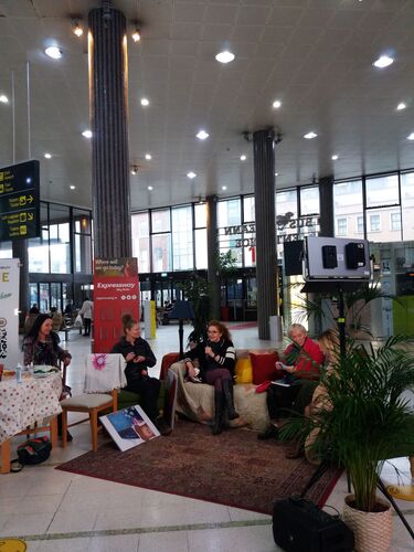 Four people sitting in a living room set in the main atrium of Busáras