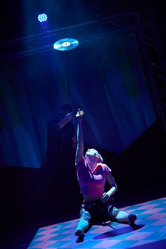 Ivonne Kalter sitting on the floor on stage reaching upwards