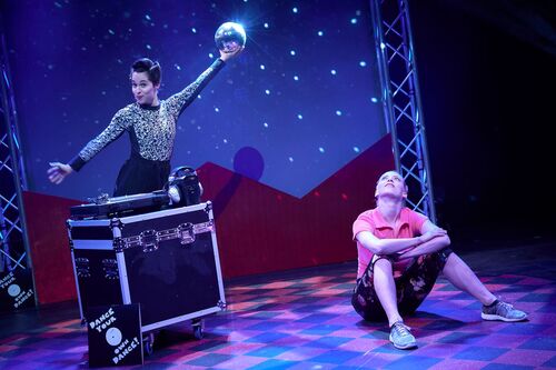 Ivonne Kalter sitting on stage on the floor with Stephanie Dufresne holding a discoball overhead