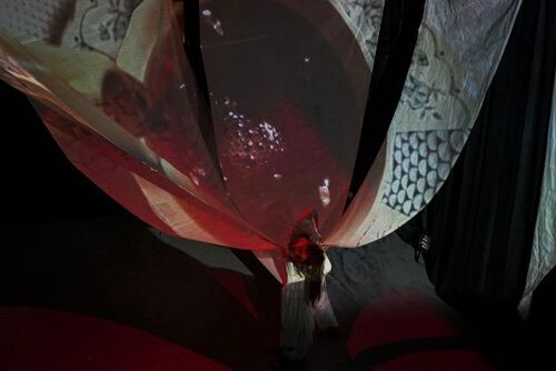 Rosie Stebbing at the base of large ship-sails being projected on