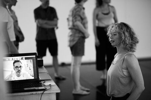 Justine Cooper in a studio looking towards a laptop with someone on a video call on screen