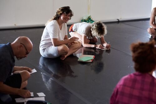 People seated on a studio floor writing