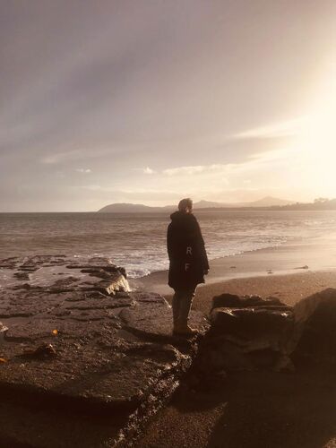 A figure standing on a beach in sepia tones