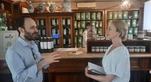 Justine Cooper in conversation with a person inside a shop