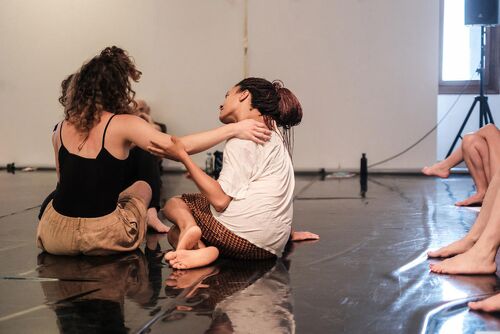 Dancers seated on the floor, in movement