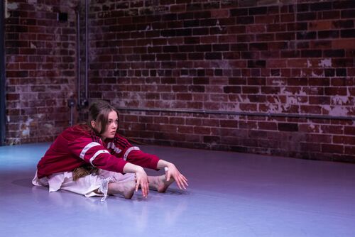 Rosie Stebbing stretching on the studio floor in CoisCéim
