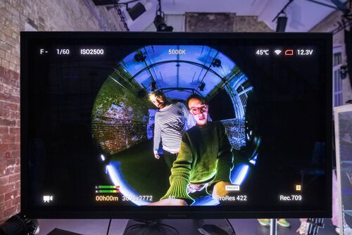 A monitor displaying a view of two people through the 360 degree VR lens