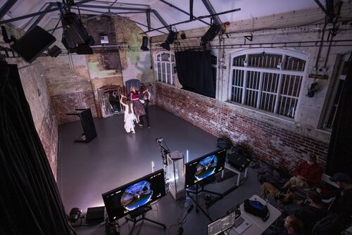 A shot from above of three dancers being filmed with two monitors either side of the camera