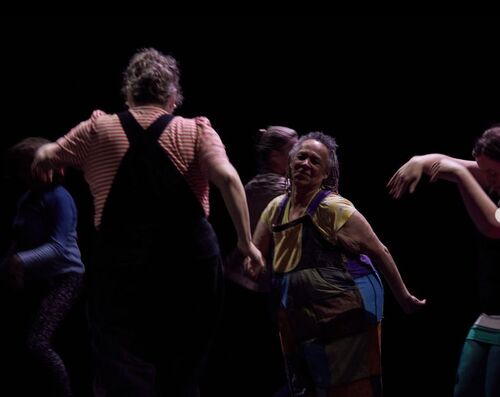 Participants in movement on a dark stage