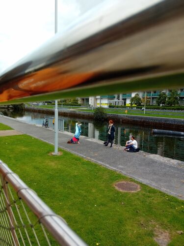 Jessie Thompson in a headstand at the side of the canal seen between railings