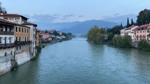 A river cutting through a town with mountains in the background