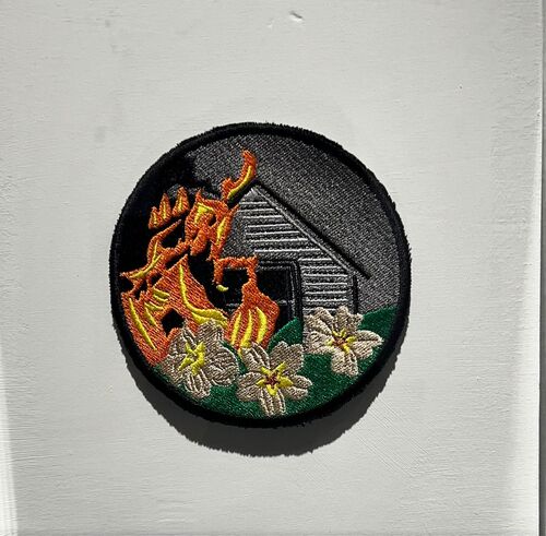 An embroidered disc of a building on fire