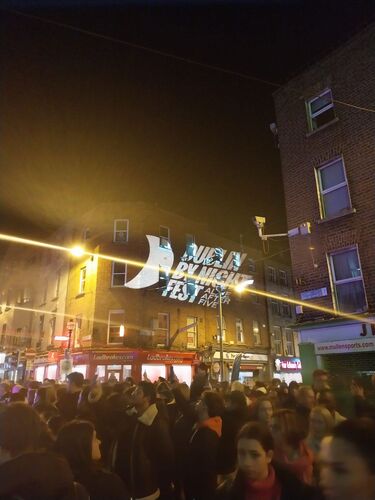 A Dublin street at night with 'Dublin By Night Fest' projected on a building