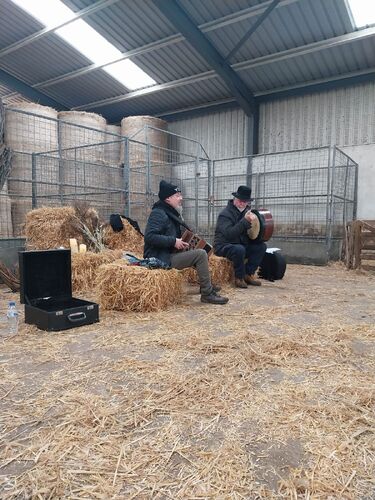 Two musicians sitting on hay bales in a barn