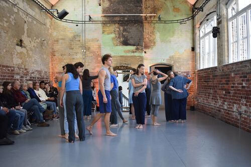 An ensemble of participants in movement in the CoisCéim studio with audience along the wall