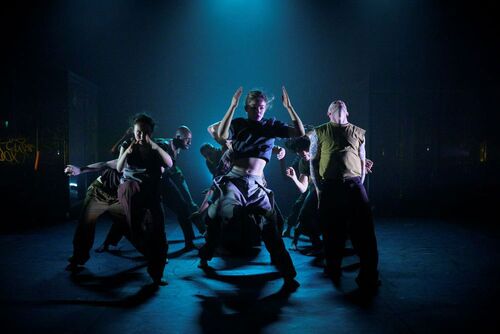 An ensemble of dancers in movement on stage