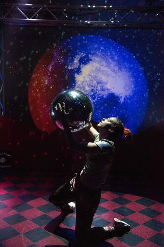 Ivonne Kalter in movement holding a large disco ball aloft