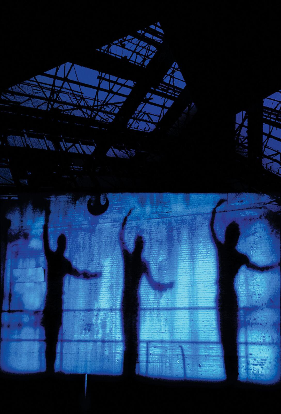 A wall cast in blue light with three shadowed figures cast on it