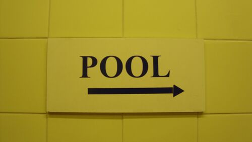 A yellow sign reading 'POOL' with an arrow to the right