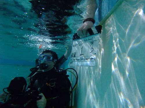 A camera operator with a snorkle and film-slate under water