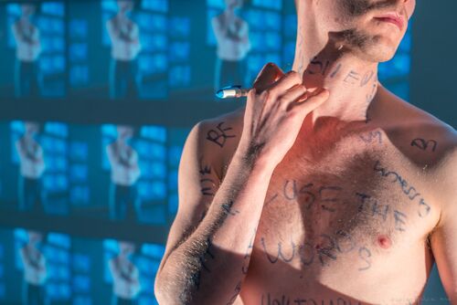 Ryan O'Neill's torso as he writes words on his skin with a marker