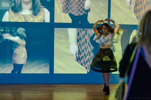 A child audience member dancing in front of a wall of projections