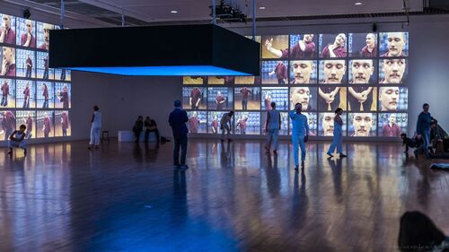 A gallery space with audience and dancers spread throughout