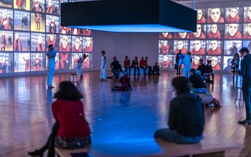 A gallery space with audience and dancers spread throughout the space