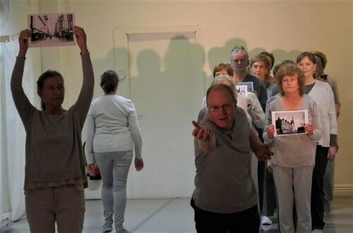 An ensemble of participants with one reaching towards camera and another holding a photo