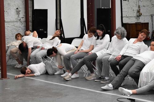 An ensemble of participants sitting in a line as though asleep