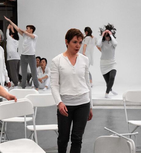 One person walking between white chairs with others dancing in the background