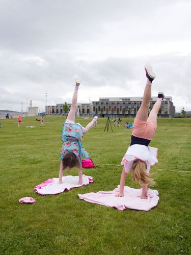 Two children doing handstands on towels on a sports field