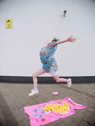A child in explosive movement over a bright pink towel on the ground