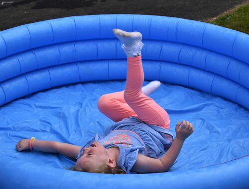 A child laughing in the middle of an empty inflatable blue paddling pool