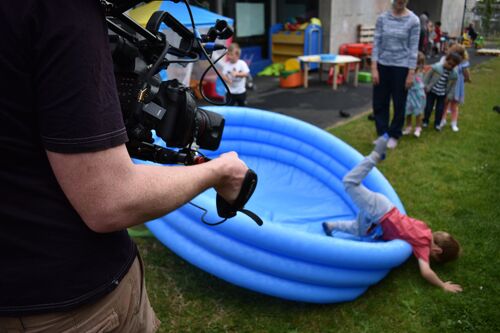 A child tumbling from an empty blue inflatable paddling pool