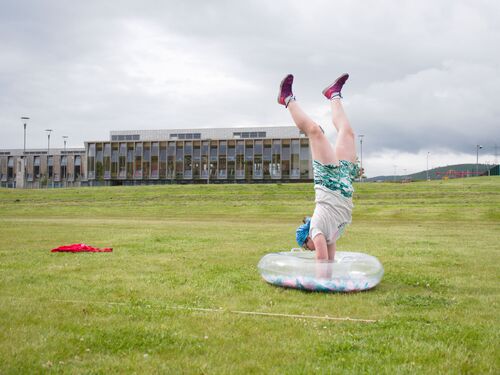 A child doing a handstand in the centre of an inflatable ring on a sports field