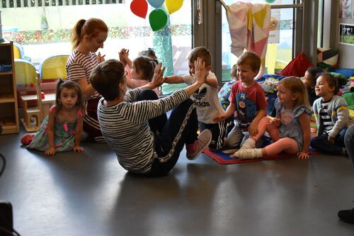 Philippa Donnellan and Olwyn Lyons playing with children on the floor in a creche