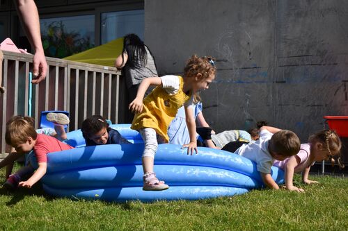 Children playing in an empty inflatable blue paddling pool