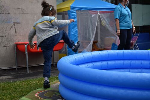 A child jumping out of an empty inflatable blue paddling pool