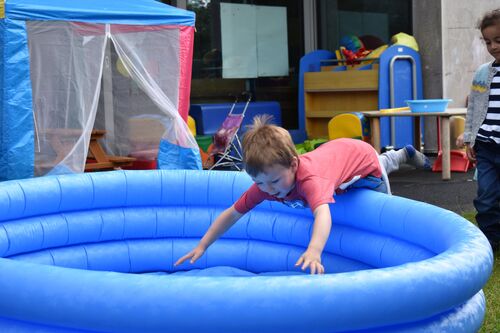 A child jumping into an empty inflatable blue paddling pool