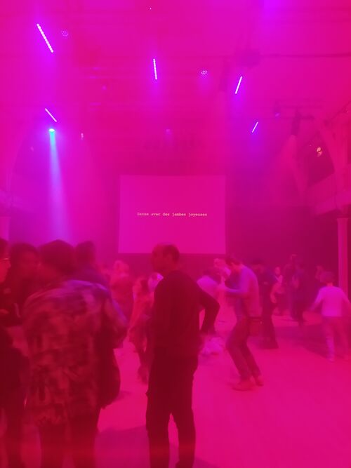 A dance floor lit in pink with figures dancing