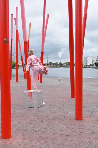Sibéal Davitt in movement on top of a mirrored cube among the Red Sticks at Grand Canal Dock