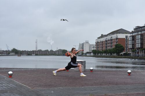 Sibéal Davitt in a lunge, arms stretched with a seagull flying overhead