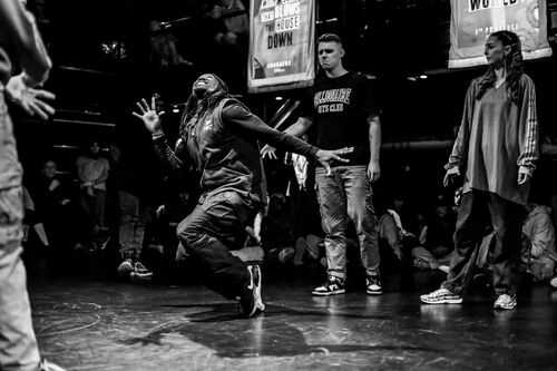 A dancer in movement with others watching on in black and white