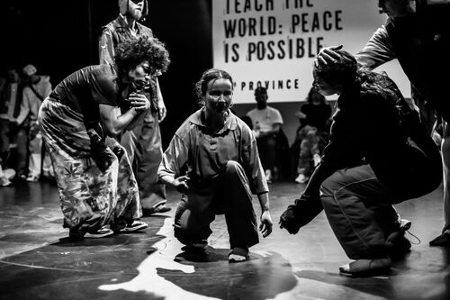 Four dancers in movement low to the ground in black and white