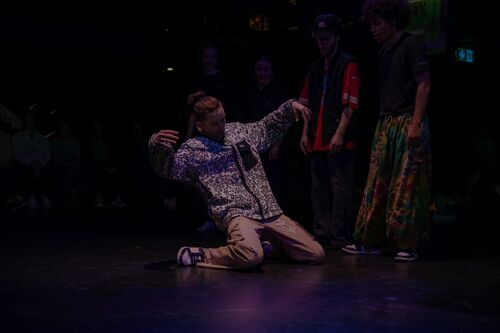 A dancer in movement on their knees on the floor