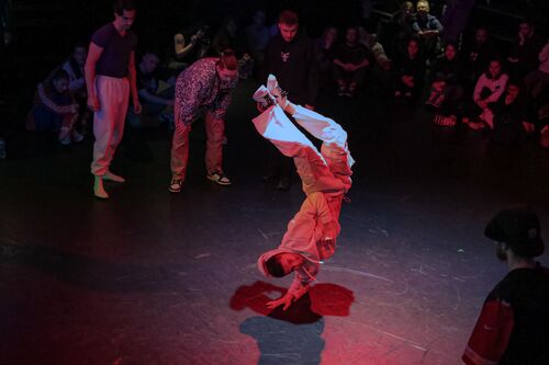 A dancer in movement in a handstand on one arm