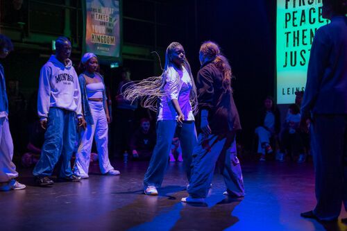 Two dancers in movement facing each other with others flanking one side behind