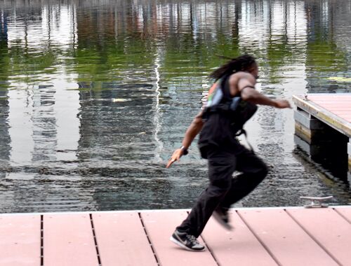 A figure blurred in movement running along a dock on the water